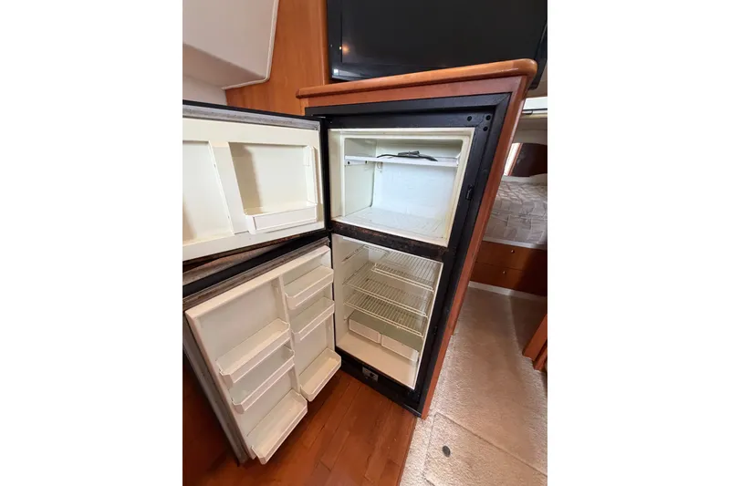 Slide: The Image of Open refrigerator inside 2002 Silverton 330 Sport Bridge yacht, showcasing ample storage space. - 29