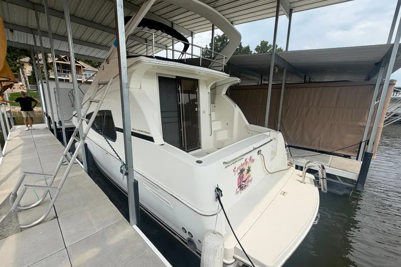 Slide: The Image of 2002 Silverton 330 Sport Bridge docked under a covered marina slip. - 3