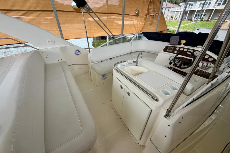 Slide: The Image of 2002 Silverton 330 Sport Bridge interior with helm, seating, and sink, docked by waterfront homes. - 11