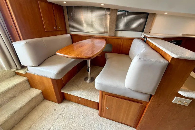 Slide: The Image of 2002 Silverton 330 Sport Bridge interior dining area with wooden table and cushioned seating. - 23