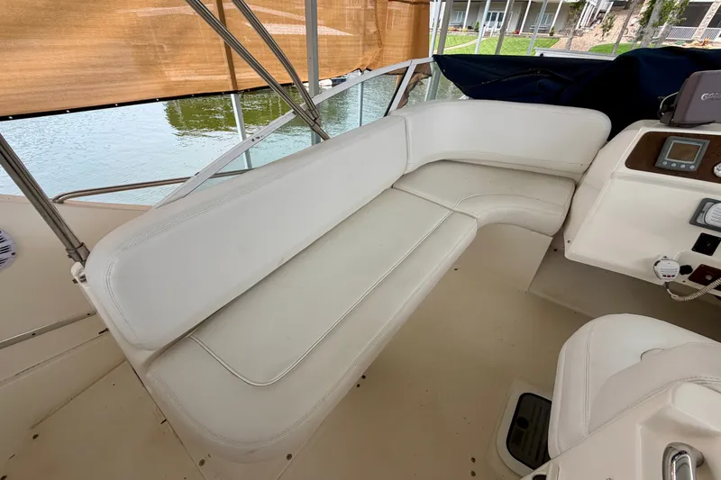 Slide: The Image of 2002 Silverton 330 Sport Bridge interior with white seating and helm, overlooking water. - 14