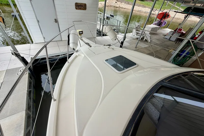Slide: The Image of 2002 Silverton 330 Sport Bridge docked at a marina with a scenic riverside view. - 6