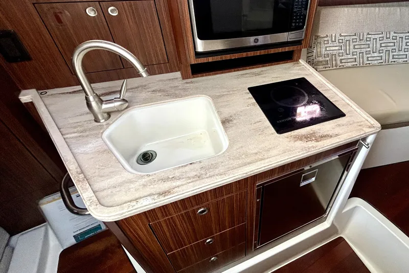 Slide: The Image of 2021 Pursuit OS 325 Offshore kitchen with sink, induction cooktop, and microwave. - 16