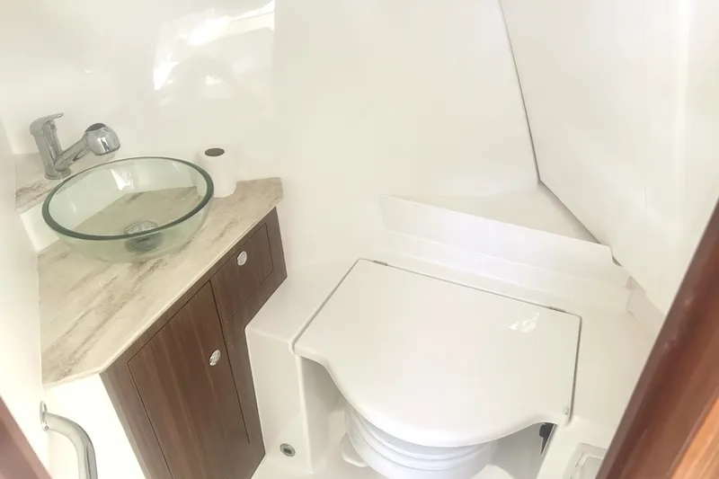 Slide: The Image of 2021 Pursuit OS 325 Offshore boat bathroom with glass sink and compact toilet. - 17