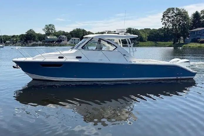 Slide: The Image of 2021 Pursuit OS 325 Offshore boat on calm water, blue and white design. - 4