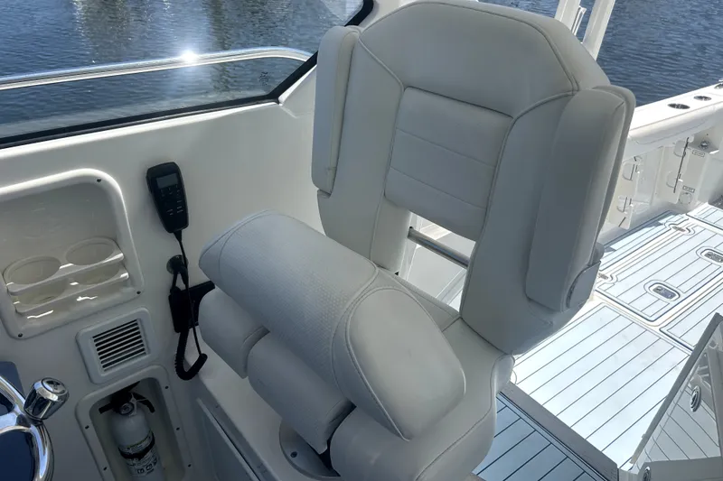 Slide: The Image of Captain's chair on 2021 Pursuit OS 325 Offshore boat, featuring white upholstery and sleek design. - 10