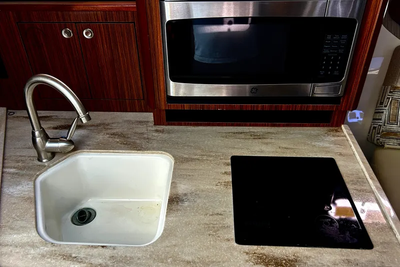 Slide: The Image of Modern kitchen area in a 2021 Pursuit OS 325 Offshore boat, featuring a sink and microwave. - 15