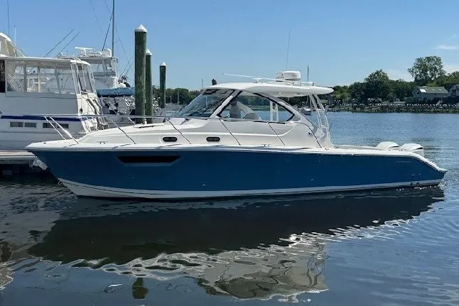 Slide: The Image of 2021 Pursuit OS 325 Offshore boat docked on calm water under clear blue sky. - 8