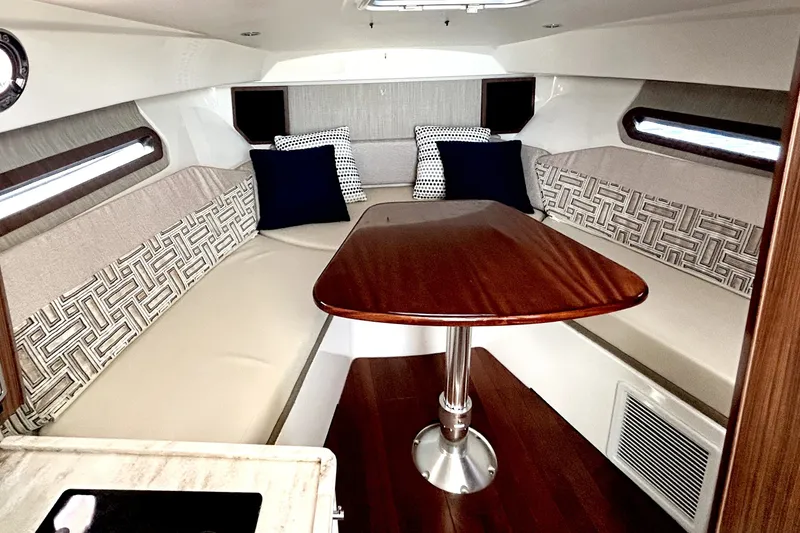 Slide: The Image of 2021 Pursuit OS 325 Offshore cabin interior with elegant seating and wooden table. - 14