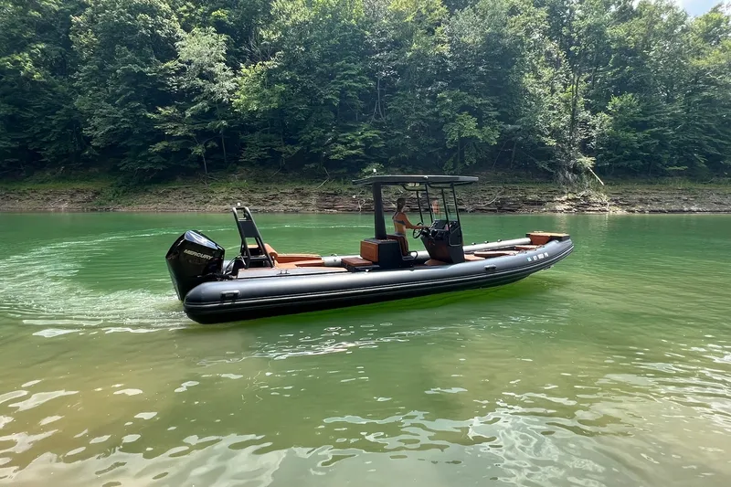 Slide: The Image of 2026 Patrol 760 RIB boat cruising on a serene lake surrounded by lush forest. - 7