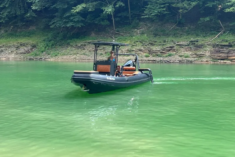 Slide: The Image of 2026 Patrol 760 RIB boat cruising on a serene green lake with forested shoreline. - 8