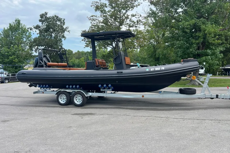 Slide: The Image of 2026 Patrol 760 RIB boat on trailer, parked outdoors with trees in background. - 19