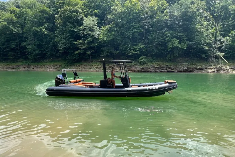 Slide: The Image of 2026 Patrol 760 RIB boat on a serene green lake with forested background. - 1