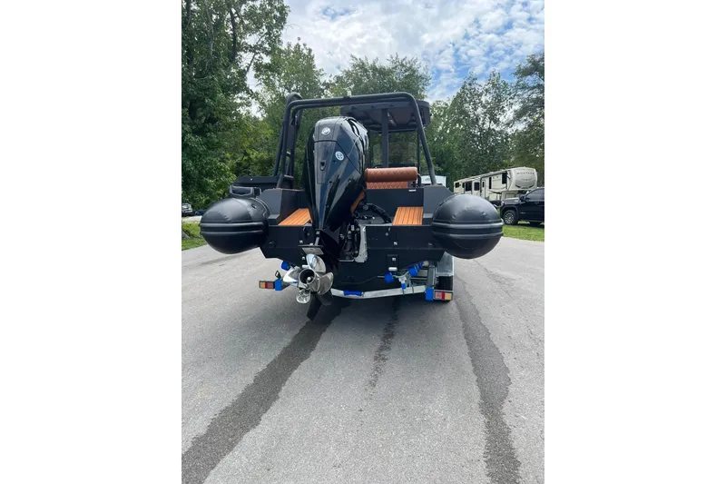 Slide: The Image of 2026 Patrol 760 RIB boat on trailer, rear view, parked on road with trees. - 23