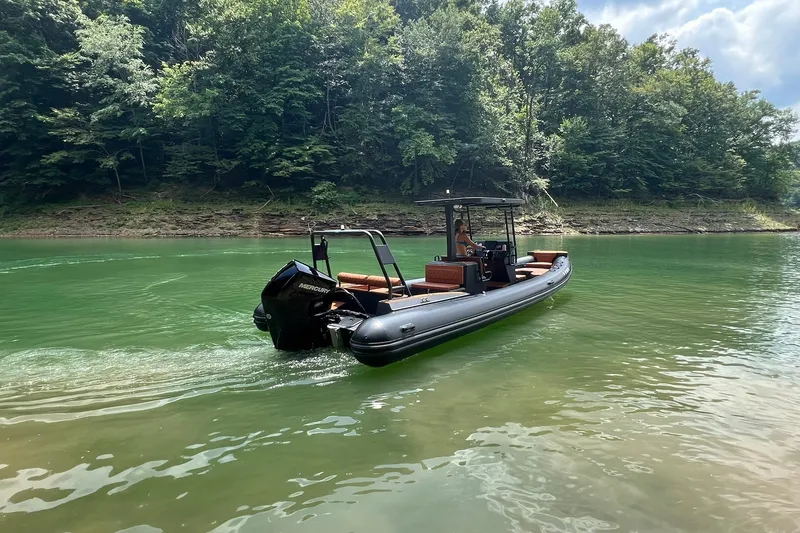 Slide: The Image of 2026 Patrol 760 RIB boat cruising on a serene lake with lush forest backdrop. - 9