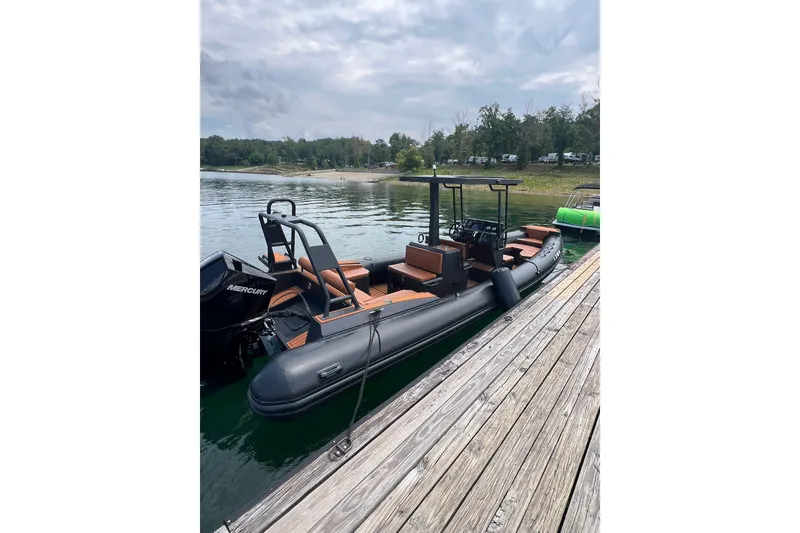 Slide: The Image of 2026 Patrol 760 RIB boat docked on a serene lake with lush greenery. - 25