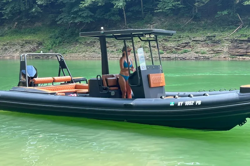 Slide: The Image of 2026 Patrol 760 RIB boat on green water, with a person standing onboard. - 2