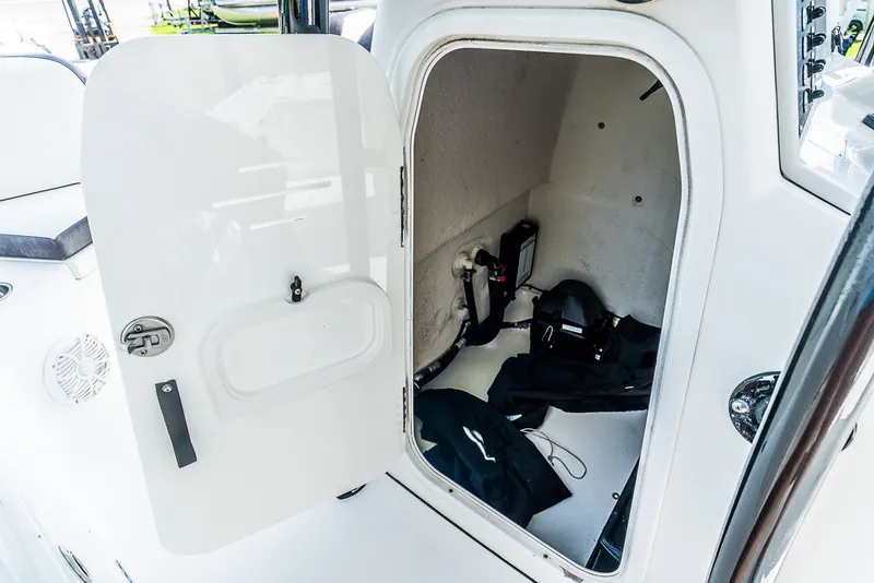 Slide: The Image of An open storage compartment on a 2019 Crevalle 24 Bay boat reveals equipment and cables. - 17