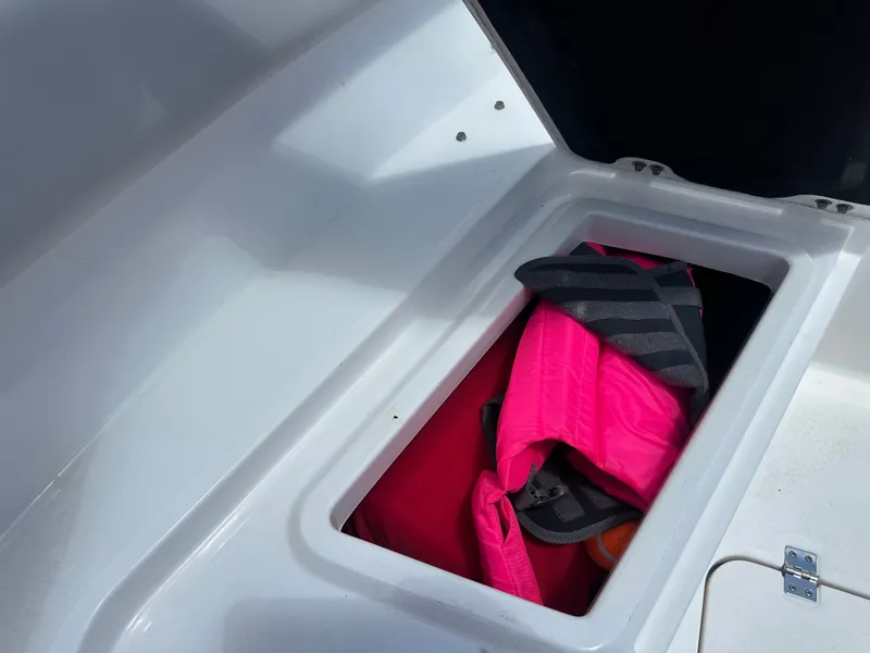 Slide: The Image of An open storage compartment on a boat with a pink life jacket inside. - 19