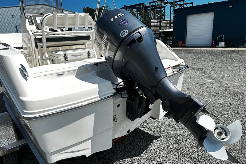 Slide: The Image of 2024 Robalo R180 Center Console boat with Yamaha 115 outboard motor, parked on gravel. - 2