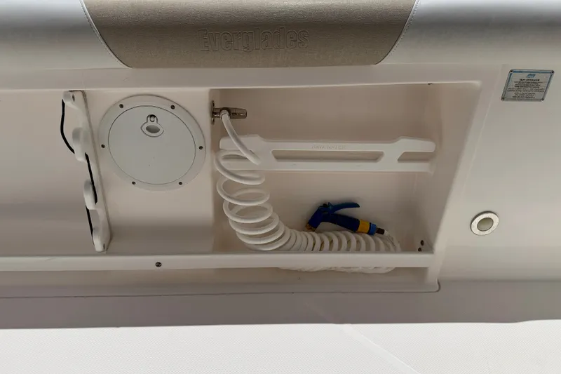 Slide: The Image of 2014 Everglades 255 Center Console boat compartment with coiled hose and nozzle. - 35