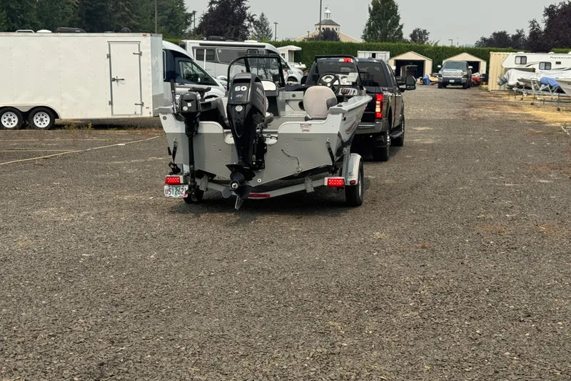 Slide: The Image of 2016 SMOKERCRAFT Osprey boat on trailer, parked in a lot with vehicles and trailers. - 22