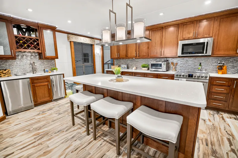 Slide: The Image of Modern kitchen with wooden cabinets, island seating, stainless steel appliances, and elegant lighting. - 10