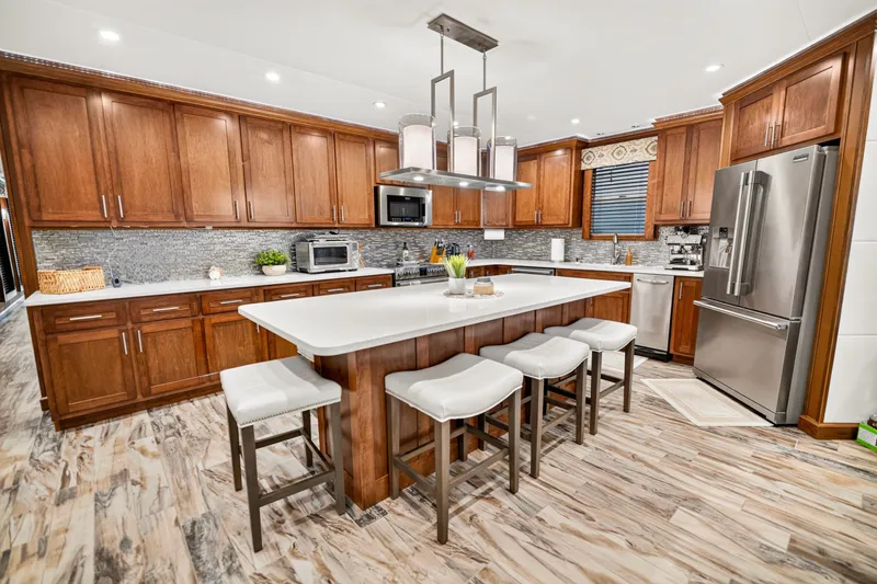 Slide: The Image of Modern kitchen with wooden cabinets, island seating, stainless steel appliances, and stylish lighting. - 11