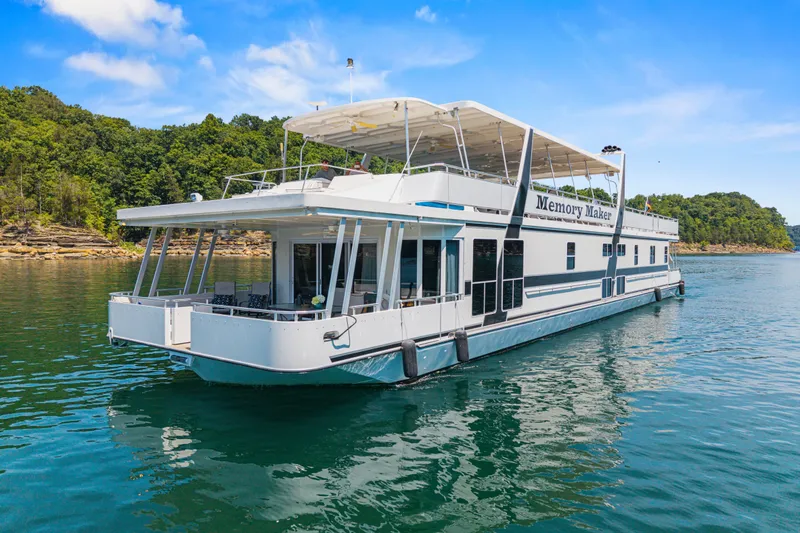 The Image of 2016 Thoroughbred 21 x 100 houseboat on a scenic lake with lush green shoreline. - 1