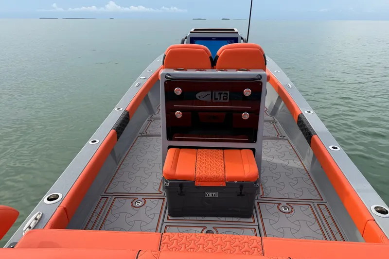 Slide: The Image of 2026 Latitude Tournament Boats 25 with orange seating and Yeti cooler on calm water. - 19