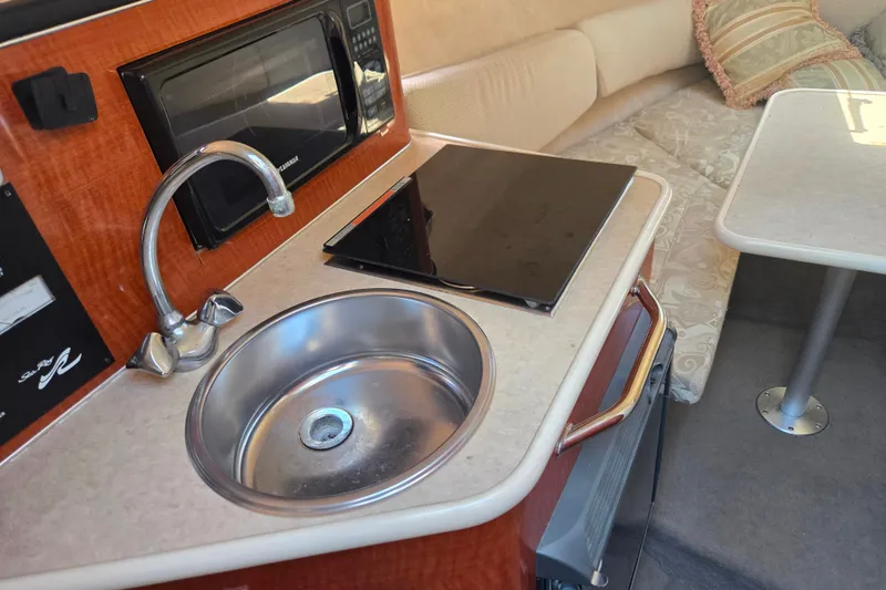 Slide: The Image of 2004 Sea Ray 240 Sundancer interior with kitchenette, sink, microwave, and seating area. - 17