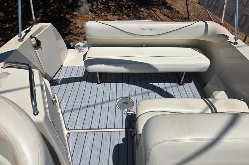 Slide: The Image of Interior of a 2004 Sea Ray 240 Sundancer boat with white seating and gray flooring. - 16