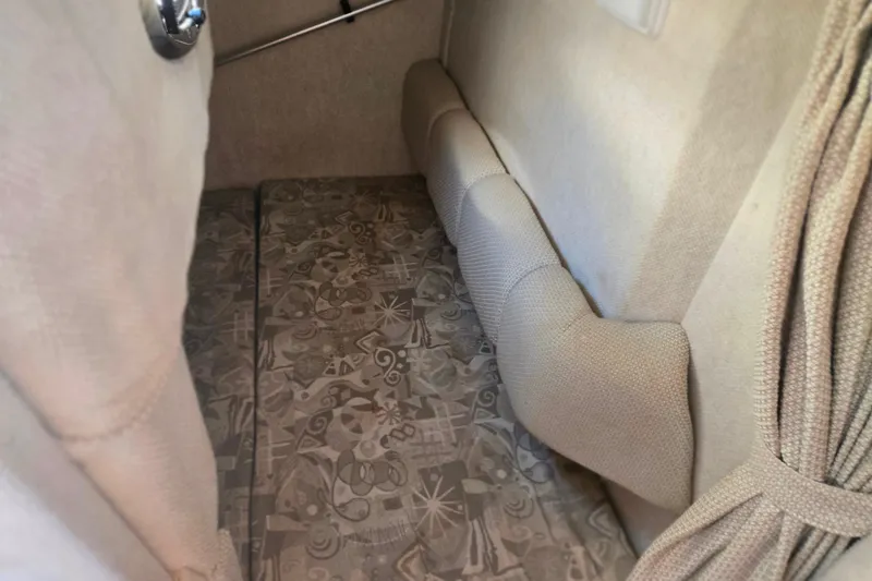 Slide: The Image of Interior cabin of 2004 Sea Ray 240 Sundancer with patterned upholstery and beige curtains. - 23