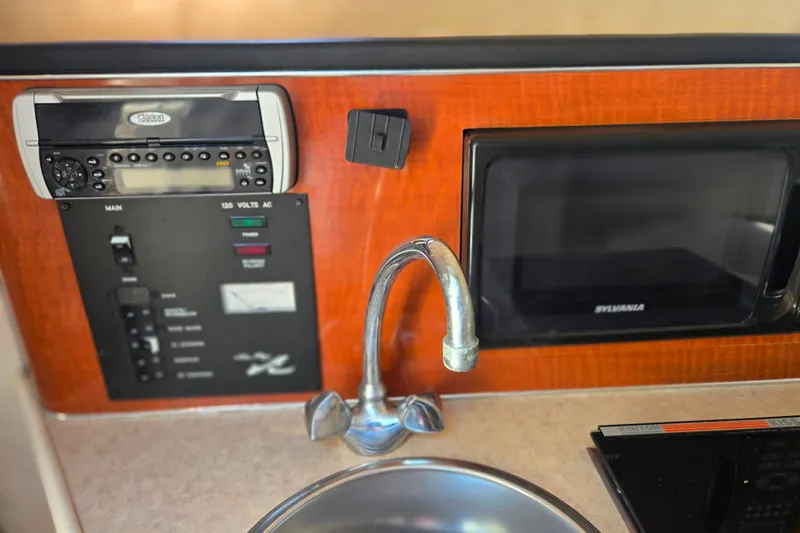 Slide: The Image of 2004 Sea Ray 240 Sundancer interior with sink, microwave, and control panel. - 21