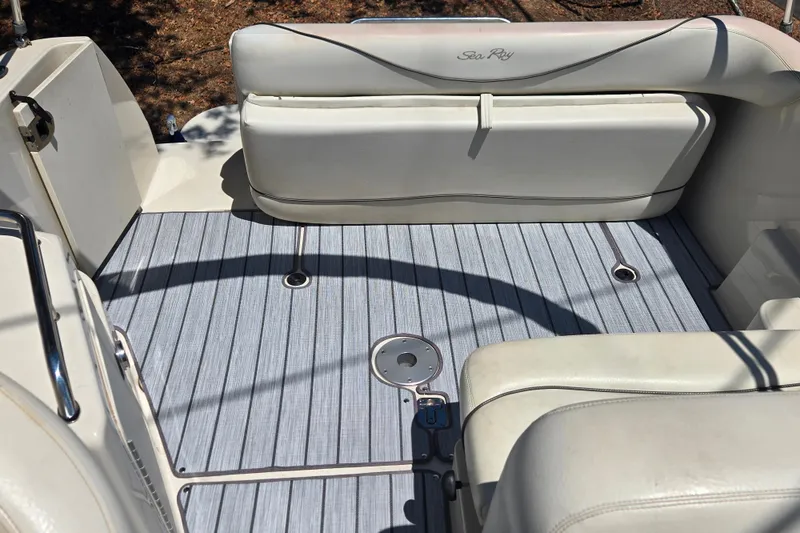 Slide: The Image of 2004 Sea Ray 240 Sundancer boat interior with cushioned seating and striped flooring. - 13