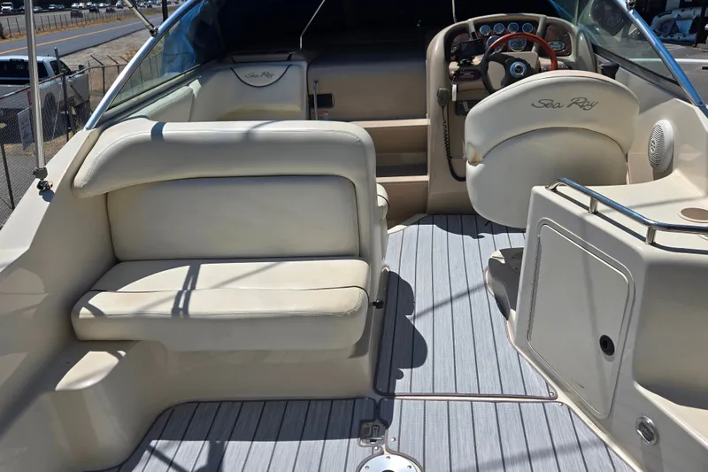 Slide: The Image of 2004 Sea Ray 240 Sundancer boat interior with beige seating and steering console. - 10