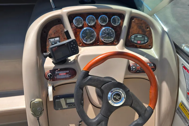 Slide: The Image of 2004 Sea Ray 240 Sundancer dashboard with gauges, GPS, and wood-accented steering wheel. - 12