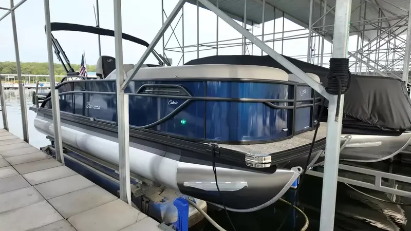 The Image of A 2027 Barletta Cabrio 22U pontoon boat is docked under a covered area. - 1