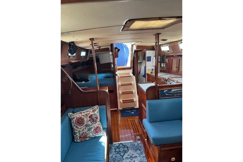 Slide: The Image of Interior of a 1987 Tartan 40 sailboat with wooden finishes and blue seating. - 13