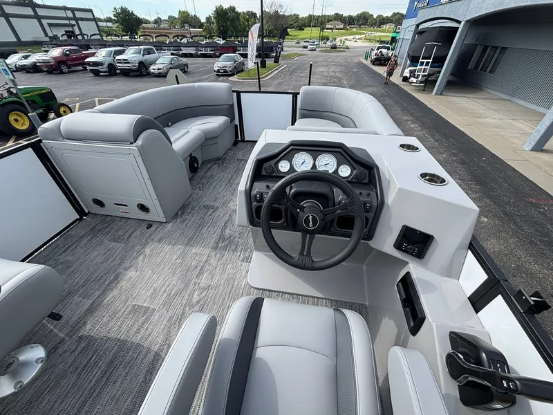 Slide: The Image of The image shows the cockpit of a 2027 Bentley Pontoons 200 Legacy Swingback. It features a modern dashboard with multiple gauges and a steering wheel. The seats are upholstered in sleek gray. Additional seating is visible in the background. - 19