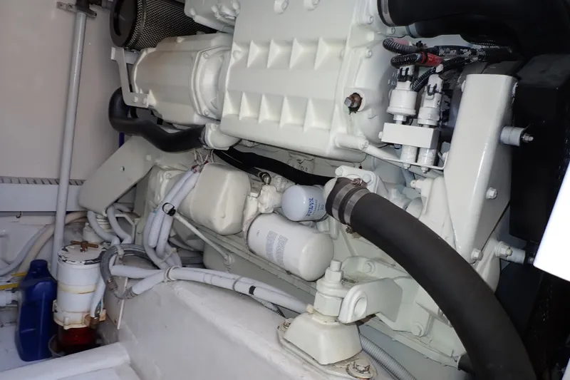 Slide: The Image of Engine compartment of a 2005 Bertram 390 boat, showcasing mechanical components and hoses. - 129
