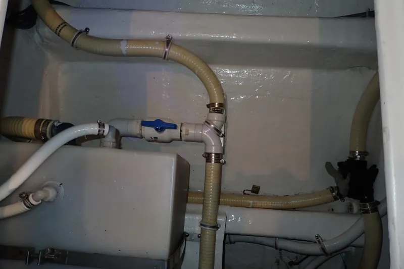 Slide: The Image of Engine room plumbing of a 2005 Bertram 390 boat, featuring hoses and valves. - 103