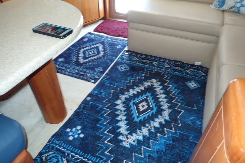 Slide: The Image of Interior of 2005 Bertram 390 with blue geometric-patterned rug and beige seating. - 77
