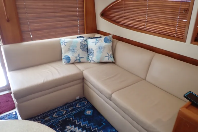 Slide: The Image of Luxurious beige sofa in 2005 Bertram 390 yacht interior with nautical-themed cushions. - 68