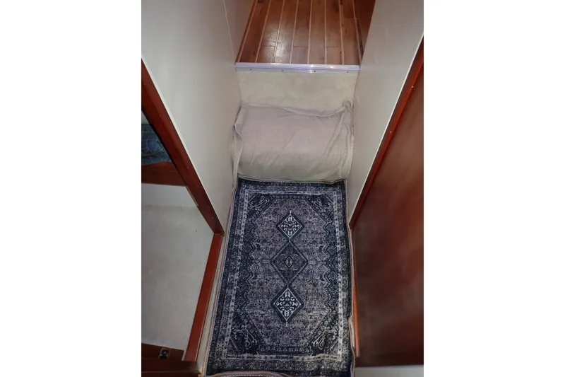 Slide: The Image of Narrow hallway in a 2005 Bertram 390 boat with a patterned rug and wooden flooring. - 96