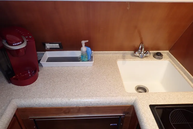 Slide: The Image of Galley kitchen in 2005 Bertram 390 with sink, faucet, and red coffee maker. - 56