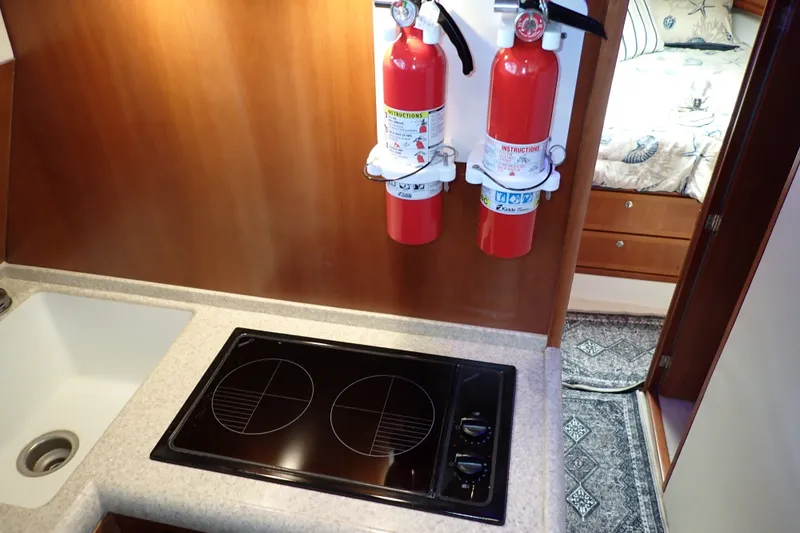 Slide: The Image of Compact kitchen area in a 2005 Bertram 390 yacht with stove and fire extinguishers. - 55