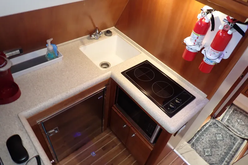 Slide: The Image of Compact kitchen area in a 2005 Bertram 390 yacht with stove, sink, and fire extinguishers. - 57