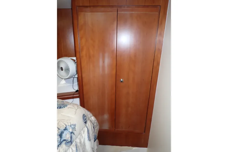 Slide: The Image of Wooden closet in 2005 Bertram 390 boat interior, next to bed with floral bedding. - 89