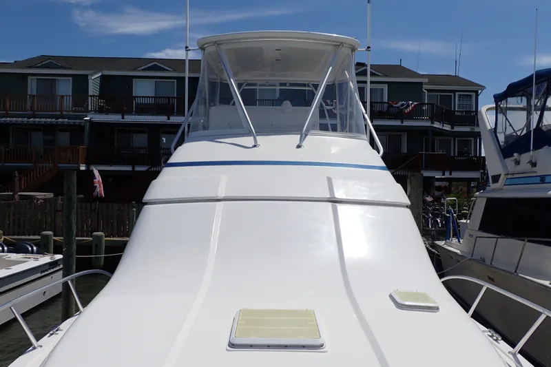 Slide: The Image of 2005 Bertram 390 yacht docked at marina, front view with clear sky background. - 30